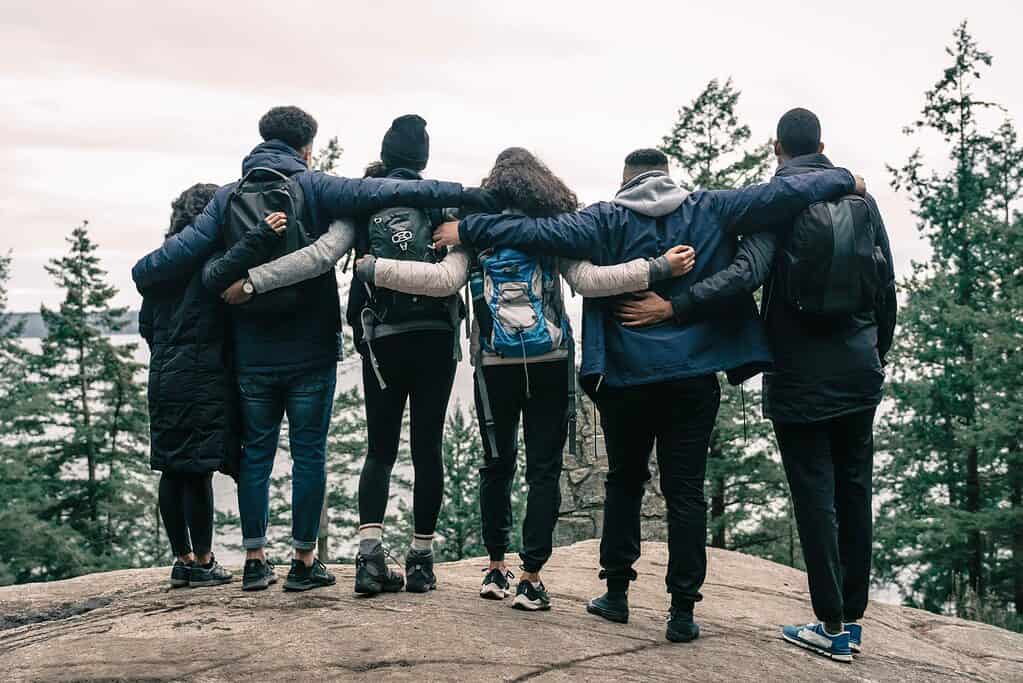 Gruppe von Personen auf einer Wanderung, die sich gegenseitig den Arm um die Schultern legen