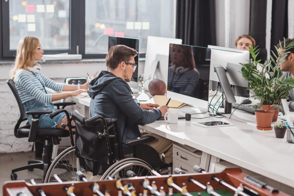 Mehrere Personen sitzen an Arbeitsplätzen in einem Büro